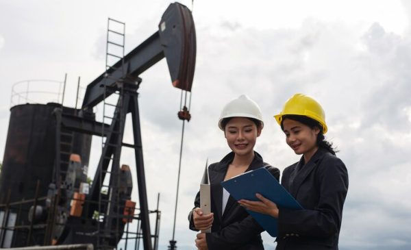 two-female-engineers-stand-beside-working-oil-pumps-with-white-sky_1150-19226